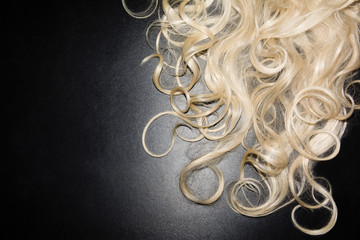 white curly hair on a black background. blonde wig. top view background