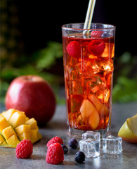 Iced tea with tropical fruits on dark background