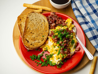 Jajecznica ze skwarkami i szczypiorkiem. Chrupiący chleb i kawa. Widok z góry, białe tło.