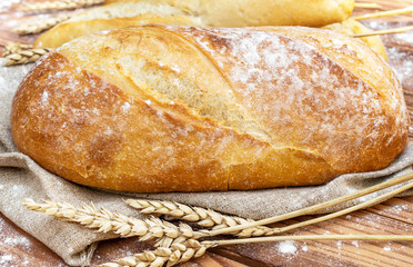 Fresh bread with wheat ears on the table. Close up.