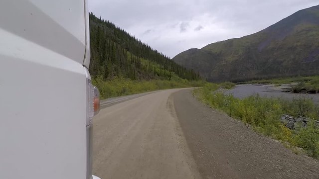 Front pov low shot on the side of a commercial work truck driving off road next to a river.  Dempster Highway, Canada.