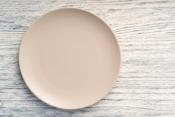 Empty beige dish on a white wooden table. Copyspace for menus and titles
