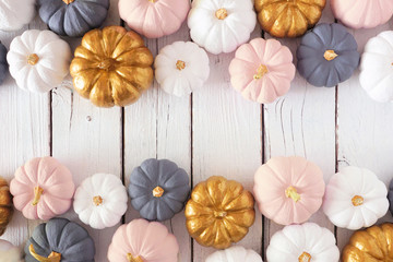 Autumn double border of dusty rose, white, gold and gray pumpkins on a white wood background. Modern muted pastel colors. Top view with copy space.