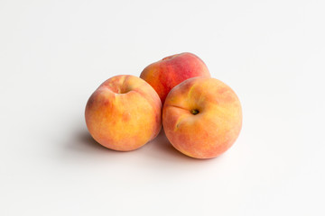 Three fresh yellow peaches centered and isolated on a white background.