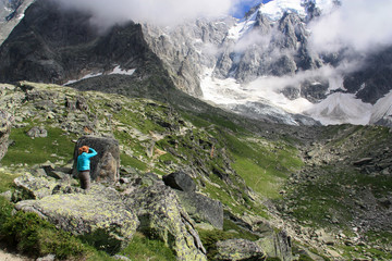 Redhead woman standing in between boulders and rocks exploring the scenic Mont Blanc massif in...