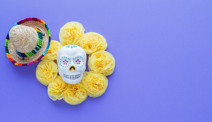 Mexican skull surrounded by yellow paper cempasuchil flowers on violet background. Day of the Dead....