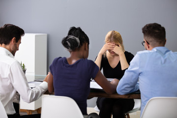 Unhappy Woman Sitting In Front Of Managers In Office