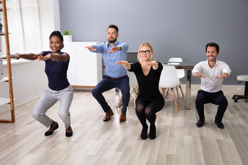 Young Businesspeople Doing Sit-ups In Office
