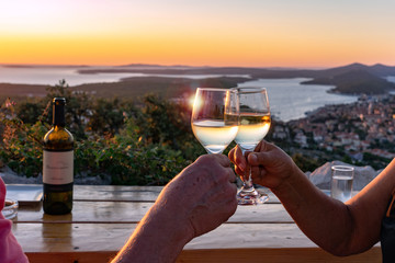 making a toast with wine over a scenic view of the croatian losinj islands in the kvarner gulf at sunset - obrazy, fototapety, plakaty