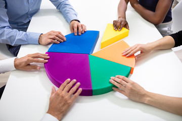 Business Executives Connecting Multi Colored Pieces Of Pie Chart