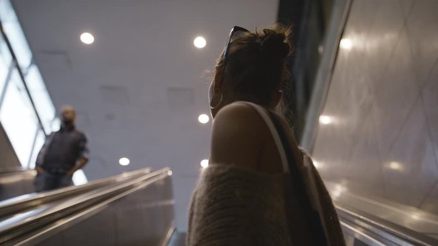 Low-angle shot of a young woman going up an escalator