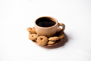 Rosquetes, a sweet made of pinol, on a traditional coffee cup made of clay.  Nicaraguan breakfast/snack. No people.