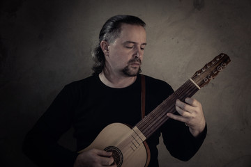 Adult man in historical suit playing vihuela....