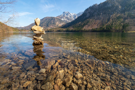 Pile of stones forming a sculpture (a so-called "Stoamandl") standing in the shallow crystal clear water of the Vorderer Langbathsee, O&Ouml;, Austria