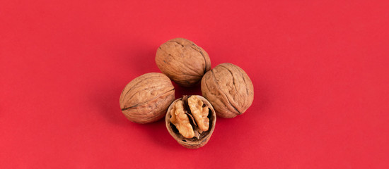 Walnuts isolated on red background. 4 walnuts with one broken.