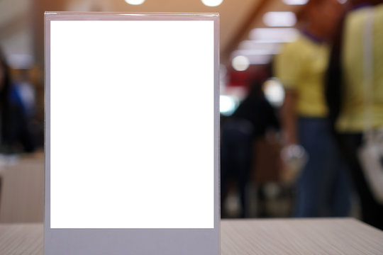 Blank mock up or label menu frame advertising in restaurant, Stand for booklets white paper sheets acrylic tent card on wood table in cafeteria, blurred background layout insert text for customer