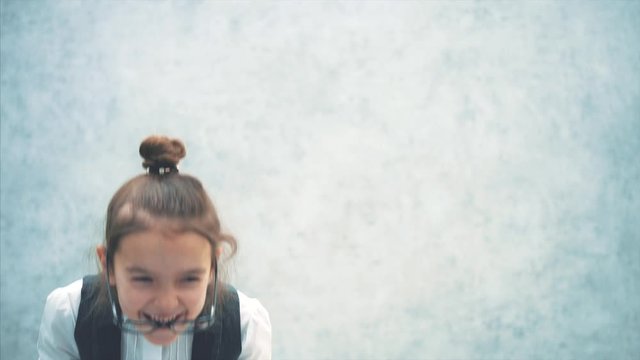 Close-up of a lady boss girl on a gray background. During this time, waving head goggles flew over to the nose. Smile. Emotional.