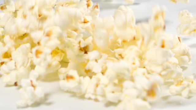 Fresh popcorn falling onto a white surface in slow motion