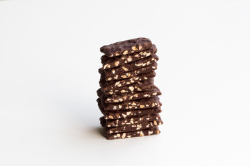 Dark chocolate bark with roasted almonds stacked up and isolated on a white background.