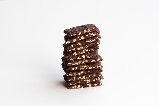 Dark chocolate bark with roasted almonds stacked up and isolated on a white background.