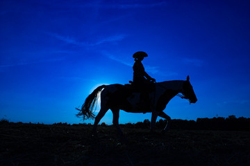 Silhouette cowgirl on horse at sunrise in blue (1)