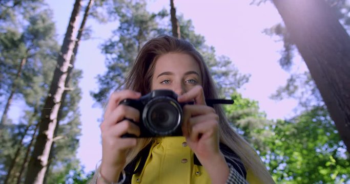  Young Smiling Woman with Camera at a Forest Festival. Female Photographer in a Woodland Glade wearing a Yellow Rain Coat. Happy, Blonde Student Girl within Green Trees at Nature Park