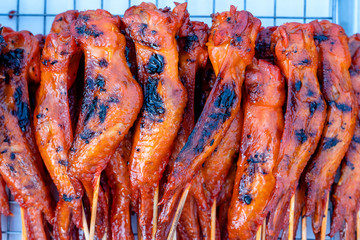 Thai street vendor sells grilled chicken meat at street food market in island Koh Phangan, Thailand. Closeup