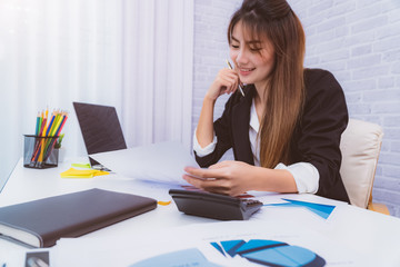 Smiling of Asia Business woman working with document graph and taking notes at office.