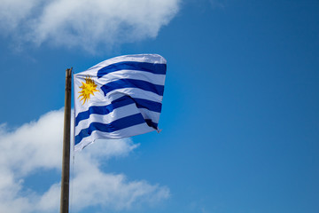  Bandeira do Uruguai no céu azul com nuvens