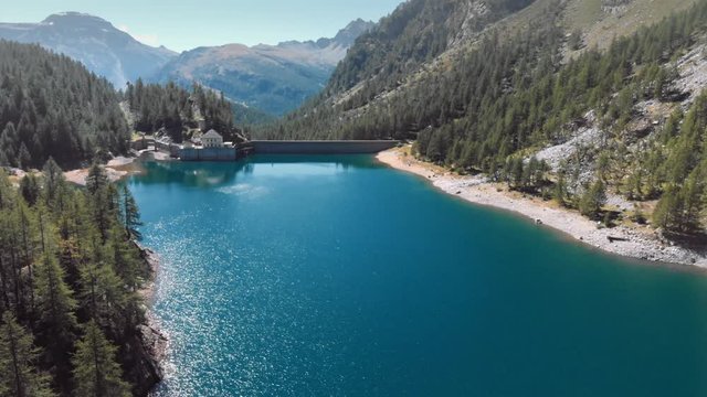 Aerial view of dam in an alpine valley, blue water reflection on the landscape. 4k