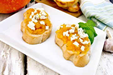 Bruschetta with pumpkin and cheese in plate on light board