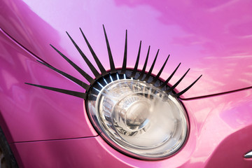 Pink car with eyelashes on headlight, closeup