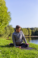 Naklejka na ściany i meble Inspired man doing yoga asanas in city park. Fitness outdoors and life balance concept.