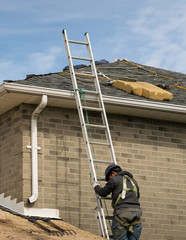 Workman ( roofer ) climibing on a lalder and going uponto the roof