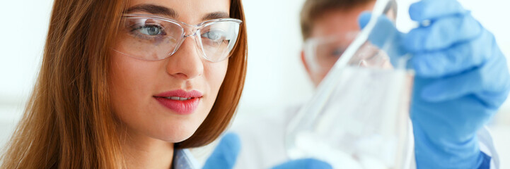 Female technician arms in protective gloves hold fluid sample bottle portrait. Medical worker in uniform use reagent tube, virus infection exam, biological toxic reaction, drug creation concept