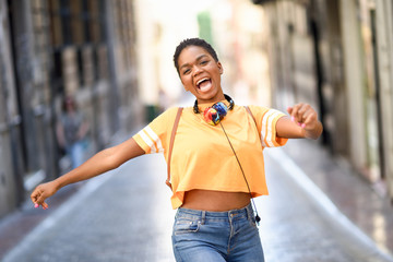 Young black woman is dancing on the street in Summer. Girl traveling alone.