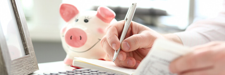 Male hands making notes with silver pen about family budget closeup