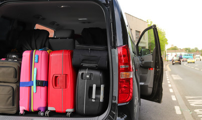 Closeup of back, rear side of black van car carrying  luggage, suitcases preparing for holiday with natural background. 