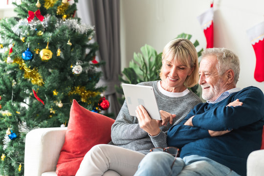 Christmas online shopping. Senior caucasian man and woman sitting on couch using tablet in living room. Happy smile.