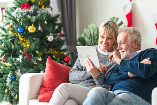 Christmas online shopping. Senior caucasian man and woman sitting on couch using tablet in living room. Happy look.