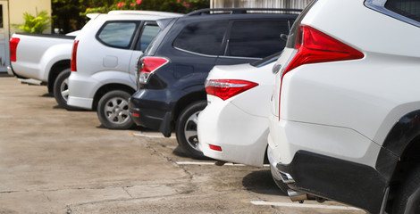 Closeup of rear side of white car with  other cars parking in outdoor parking area.