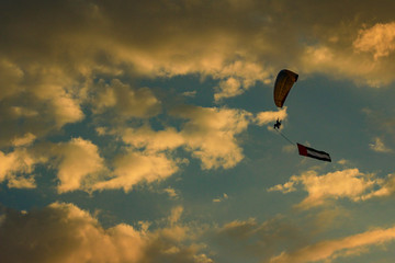 a man flying at the sunset holding uae flag, uae flag waving at the sunset, Flying paraglider with uae flag , uae flag day. united arab emirates 