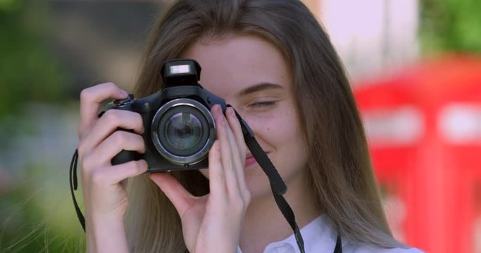 Portrait of Pretty Blonde Young  Woman with Camera taking a  Photograph. Student with Nose Piercing, Green Eyes, Long Hair and Freckles.  Student British Model Teen Girl on Summer Break.