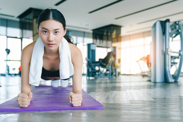 young strong asian woman wirkout exercise doing plank in gym fitness background