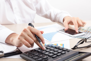 Close up of female accountant or banker making calculations. Savings, finances and economy concept