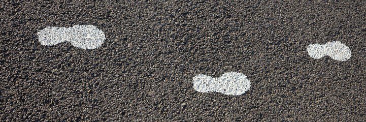 White footstep symbol painted on the asphalt ground floor to guide the tourist for the position