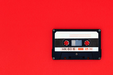 Old audio tape cassette on a bright red background. Top view, old technology concept