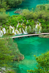 Fototapeta premium Rushing pure fresh water cascades down the natural barriers into the azure colored Lake Kaluđerovac at the Plitvice Lakes National Park in Croatia