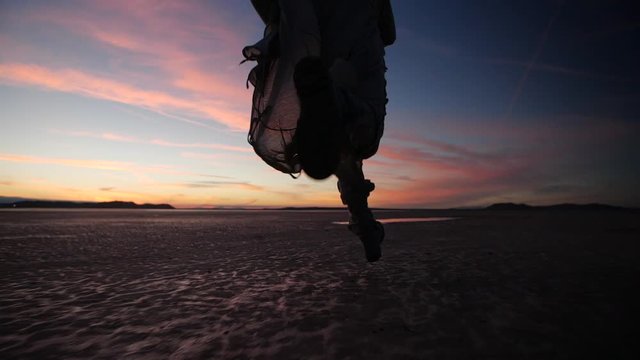 Follow running man in desert at beautiful sunset.
