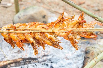 Shrimps attaching on stick grilling over stove